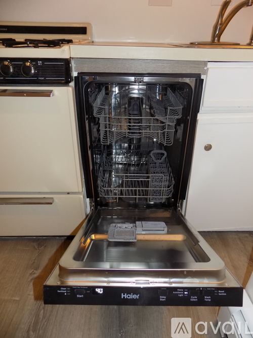 An open dishwasher is in the foreground of a kitchen.