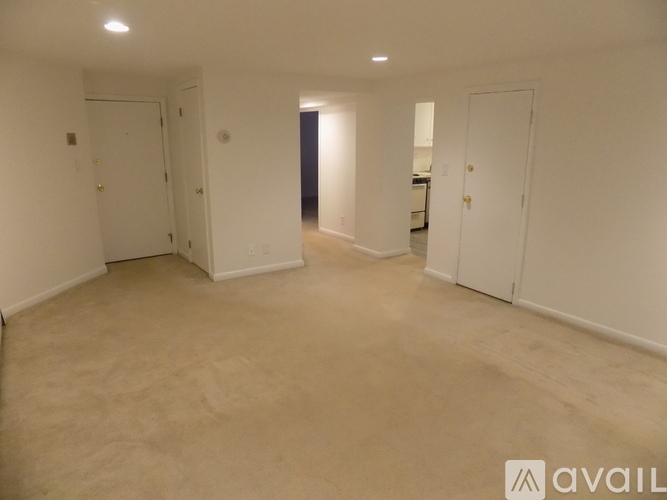 A spacious room with white walls and carpeted floor.