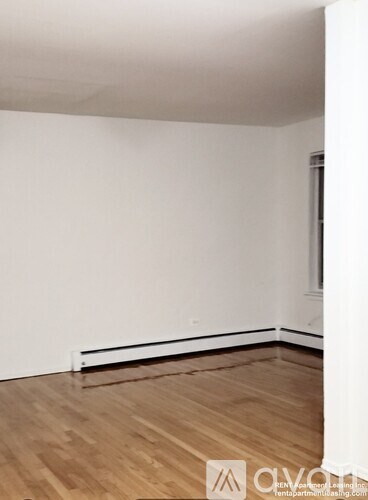 A room with wooden flooring and white walls.