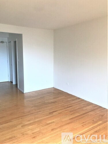 A room with wooden flooring and a white wall.