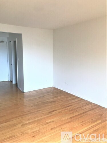 A room with wooden flooring and a white wall.