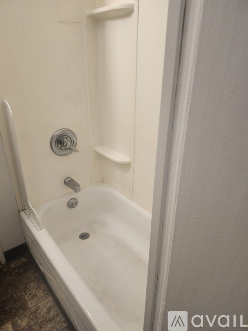 A white bathtub with a shower head and a faucet.