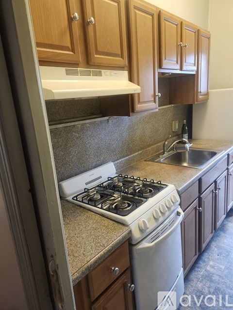 A kitchen with a white stove top oven and wooden cabinets.