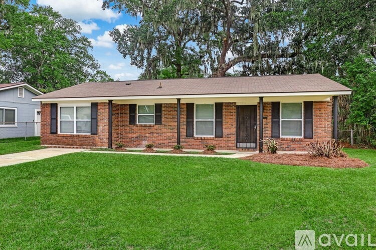 A house with a brown roof and a green lawn in front.