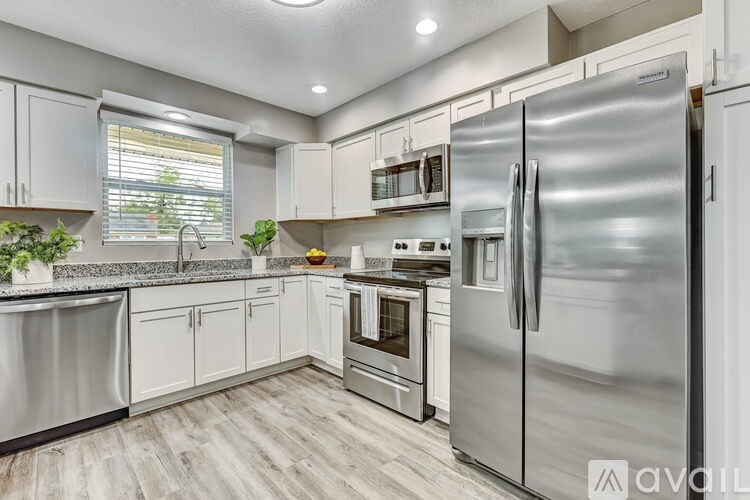 A kitchen with a stainless steel refrigerator and white cabinets.