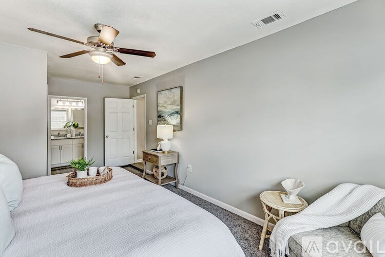 A bedroom with a bed, chair, and a ceiling fan.