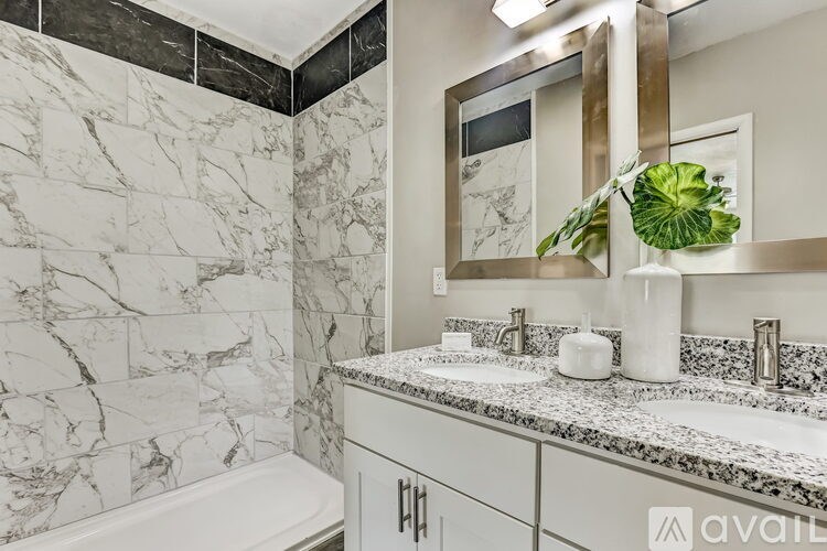 A bathroom with marble tiles and a white tub.