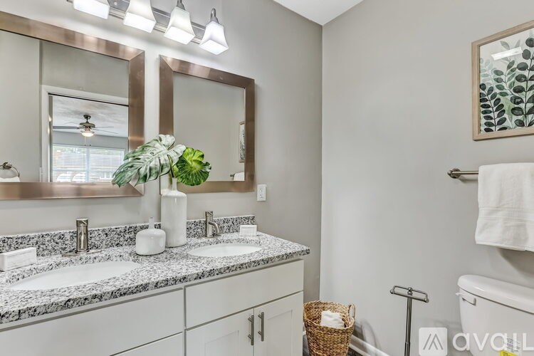 A bathroom with a marble countertop and a large mirror above it.
