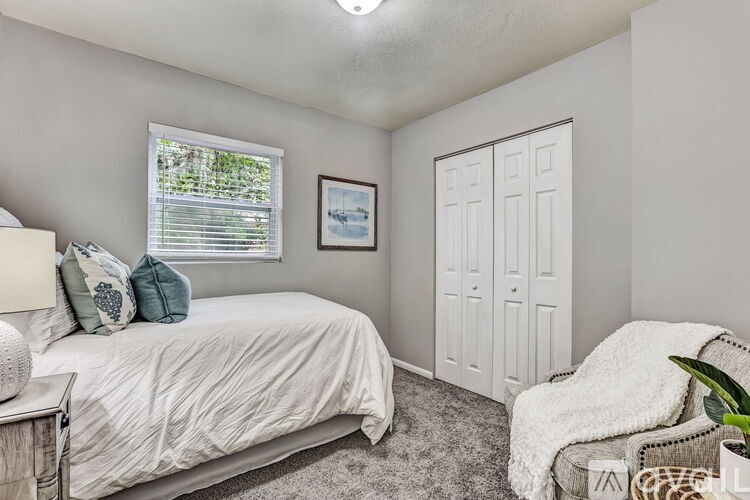 A bedroom with a bed, a chair, and a painting on the wall.