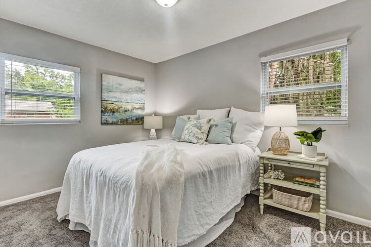 A bedroom with a bed, nightstand, and a window with blinds.