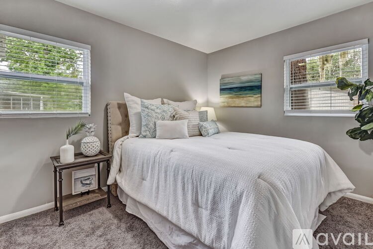 A bedroom with a large bed and a small table with a plant on it.