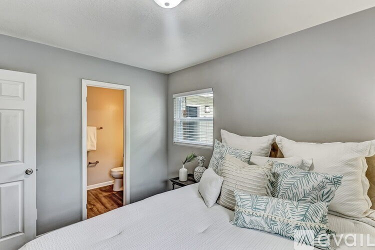 A bedroom with a bed, pillows, and a window.