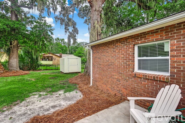 A white chair is placed on a patio in front of a brick house.