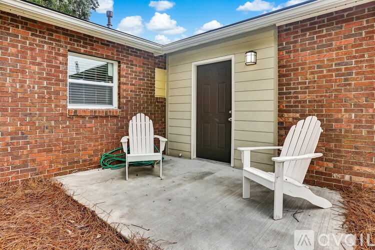 Two white chairs are placed on a concrete patio.