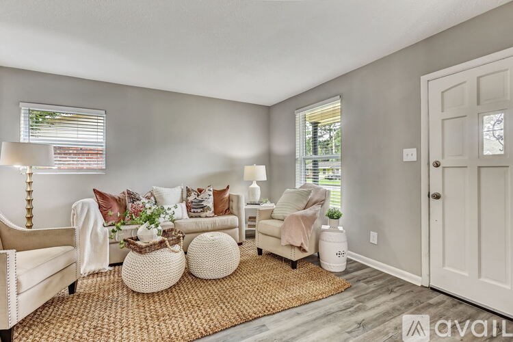 A living room with a white sofa, a white armchair, a white ottoman, and a white door.