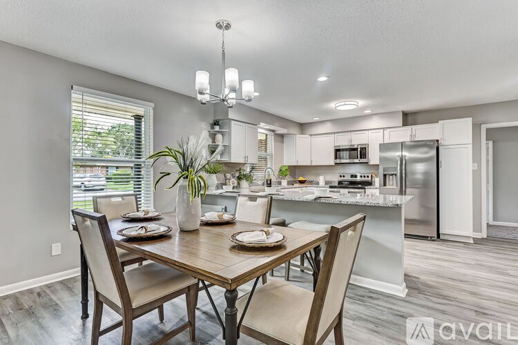 A dining room with a table set for two and a kitchen in the background.