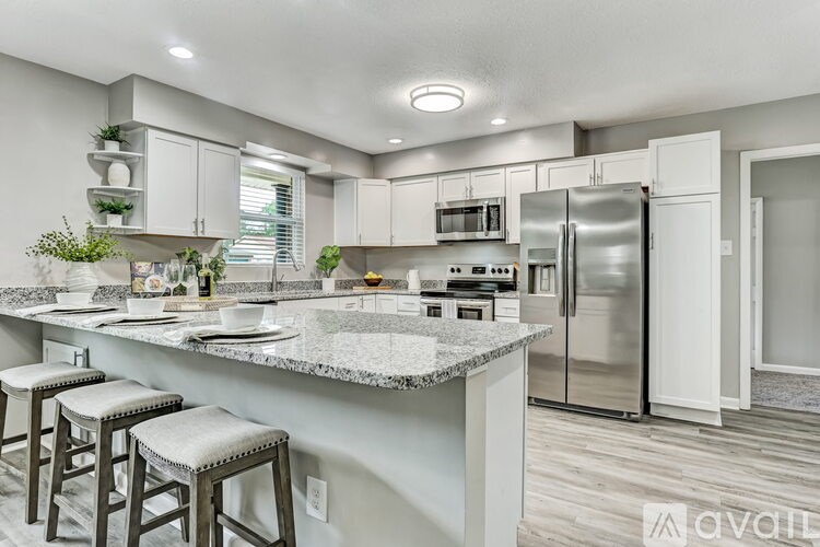 A modern kitchen with a marble countertop and stainless steel appliances.