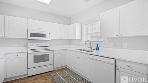 A white kitchen with a sink and a microwave.