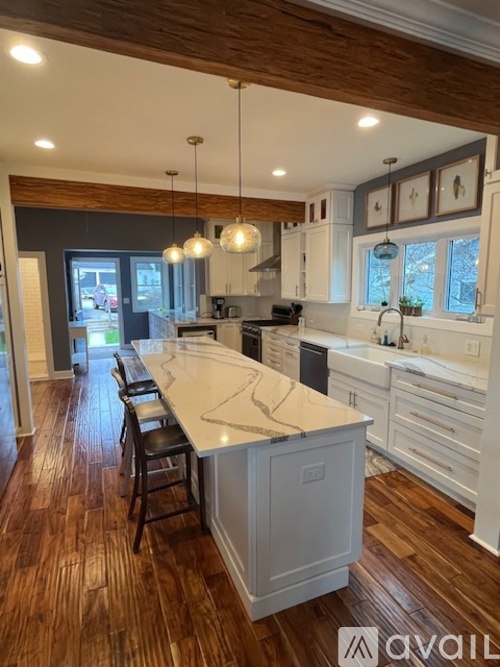 A kitchen with a white island and wooden floors.
