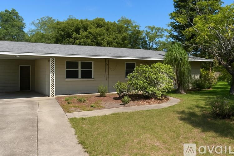A house with a driveway and a tree in front.