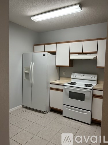 A kitchen with a white stove and refrigerator.