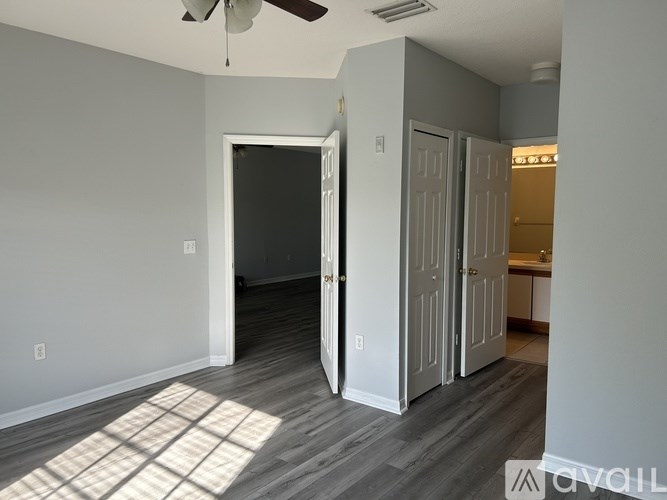 A room with a ceiling fan and a rug on the floor.