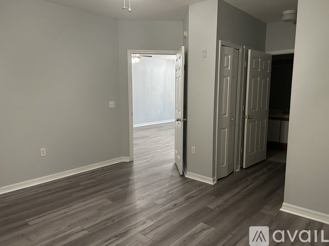 A room with wooden flooring and white walls, with a doorway leading to another room.