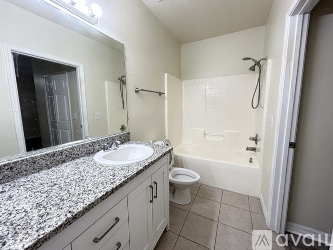 A bathroom with granite countertops and a white toilet.