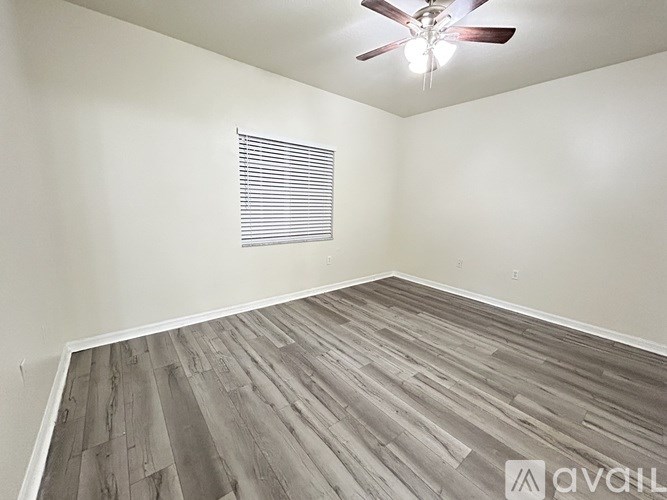 A room with a ceiling fan and wooden flooring.