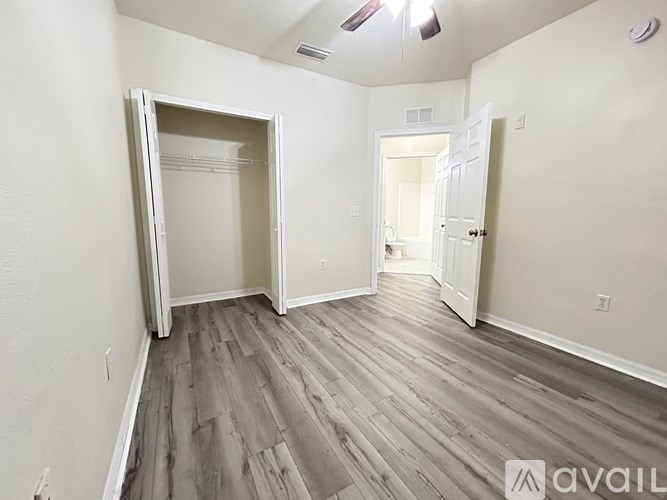 A room with a grey floor and white walls has a doorway leading to another room.