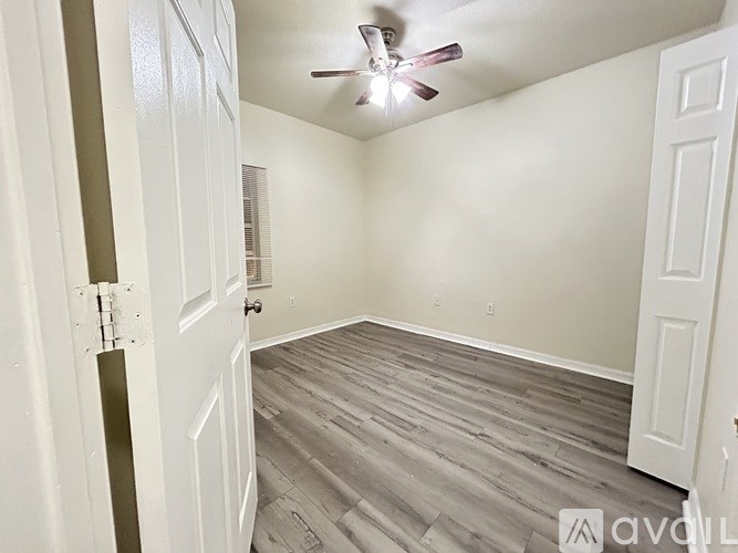 A room with a ceiling fan and wooden flooring.