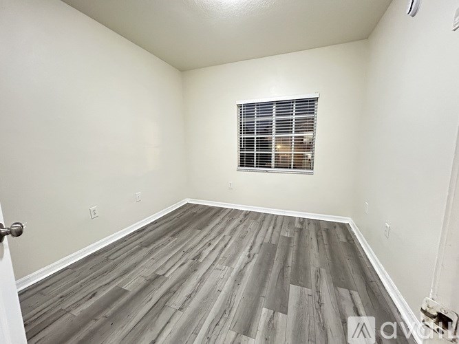 A room with wooden flooring and a window with blinds.