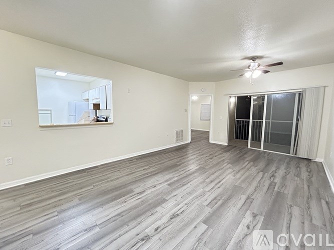 A spacious room with wood flooring and a ceiling fan.