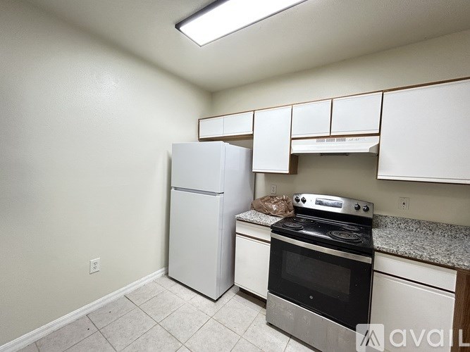 A kitchen with a stove, refrigerator, and cabinets.
