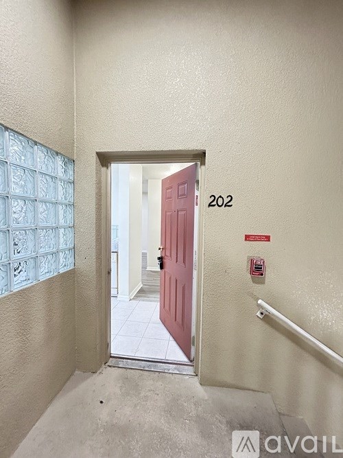 A red door with the number 202 on the wall next to it.