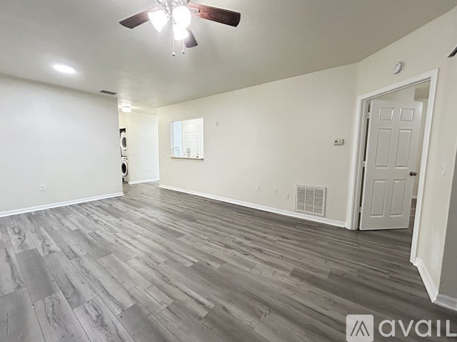 A room with a ceiling fan and wooden flooring.