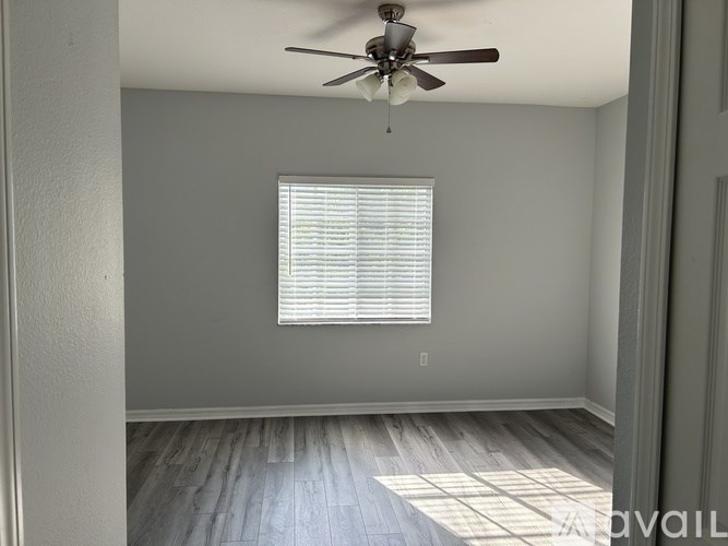 A room with a ceiling fan and a window with blinds.