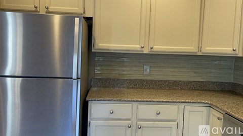 A kitchen with a stainless steel refrigerator and white cabinets.