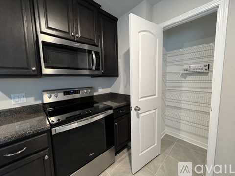 A kitchen with black cabinets and a white door.