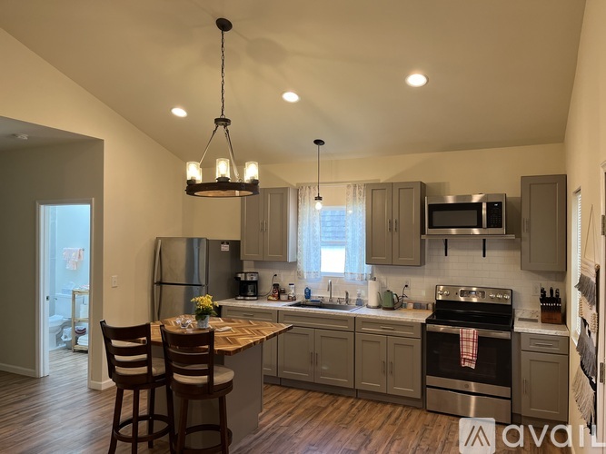 A kitchen with wooden floors and a large island with chairs.