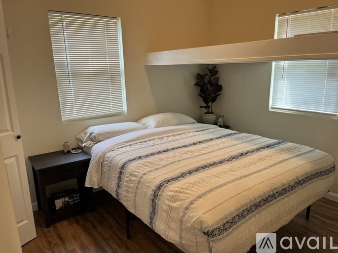 A bedroom with a bed, nightstand, and window.