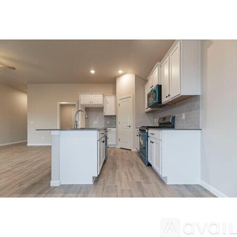 A kitchen with white cabinets and a black countertop.
