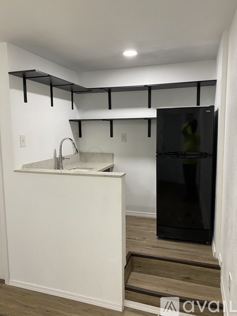 A kitchen with white walls and a black fridge.
