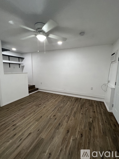 A room with wooden flooring and a ceiling fan.