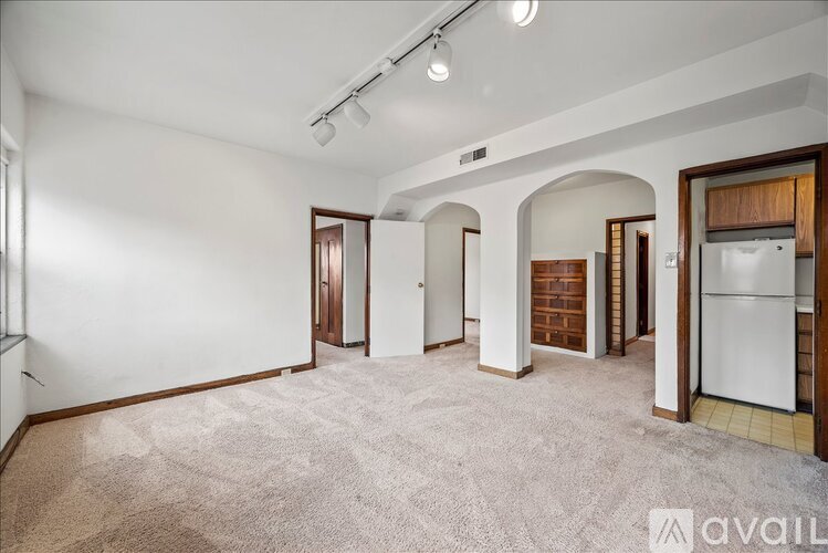 A spacious living room with a carpeted floor and white walls.