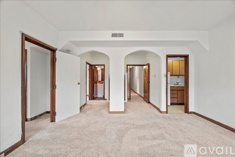 A spacious room with arched doorways and a carpeted floor.