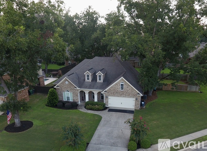 A house with a garage and a driveway is surrounded by trees.