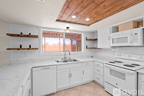 A kitchen with white cabinets and a wooden ceiling.