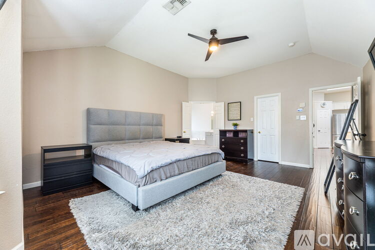 A bedroom with a bed, dresser, and ceiling fan.