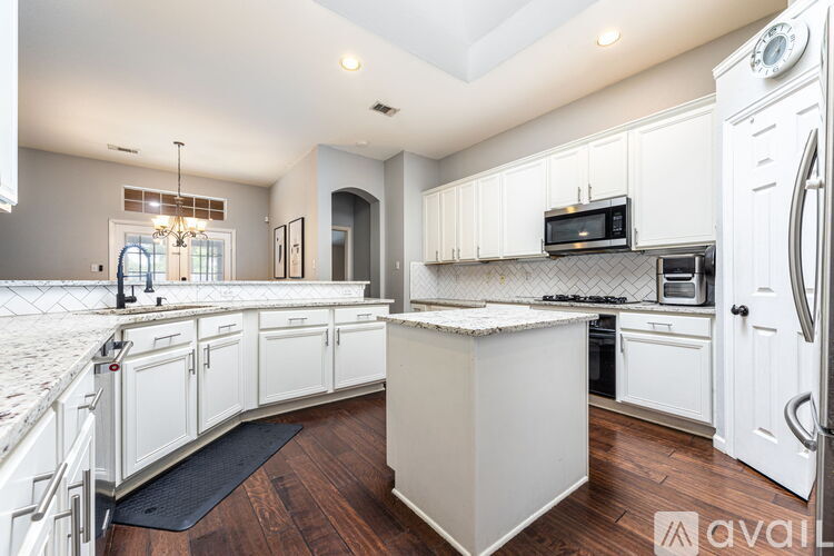 A kitchen with white cabinets and a wooden floor.